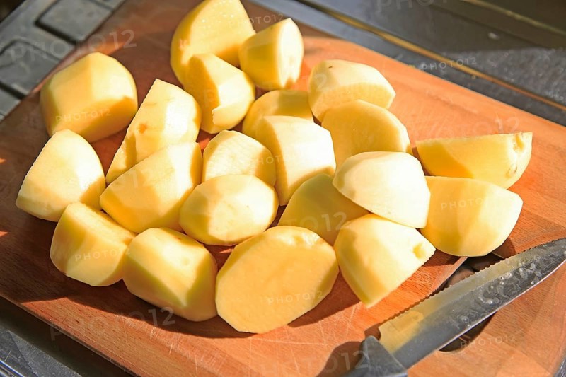 Peeled cut chopped potatoes on chopping board with kitchen knife
