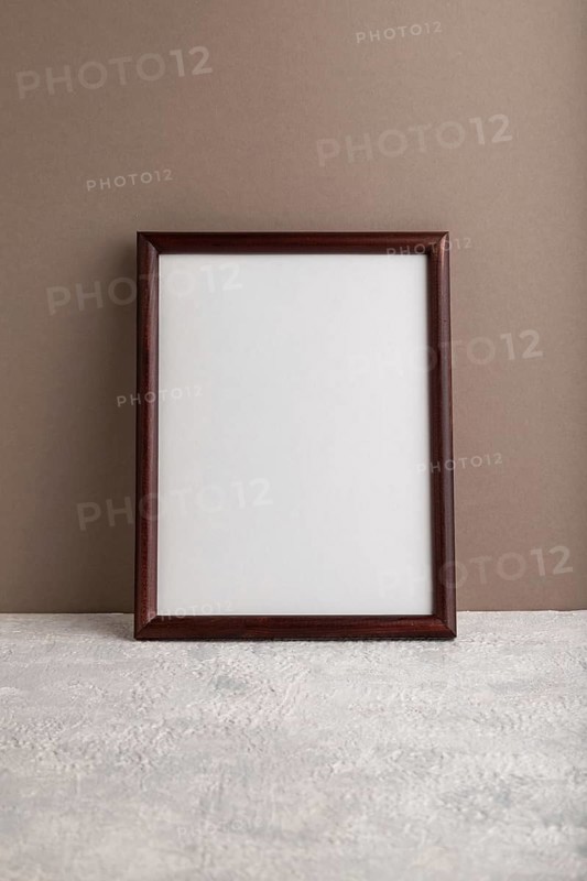 Brown wooden frame mockup on beige paper background. Blank, vertical orientation, still life, copy space