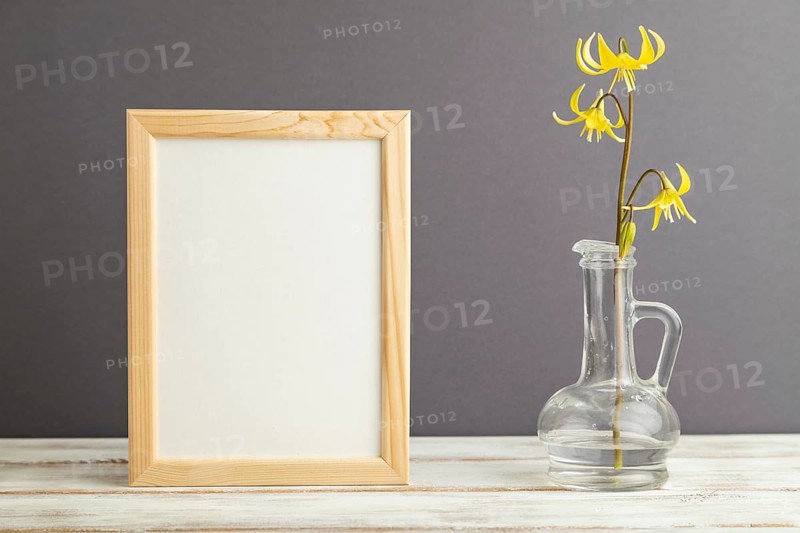 Wooden frame with yellow trout lily or dogtooth violet flowers in glass on gray pastel background. side view, copy space, mockup, template, spring, summer minimalism concept