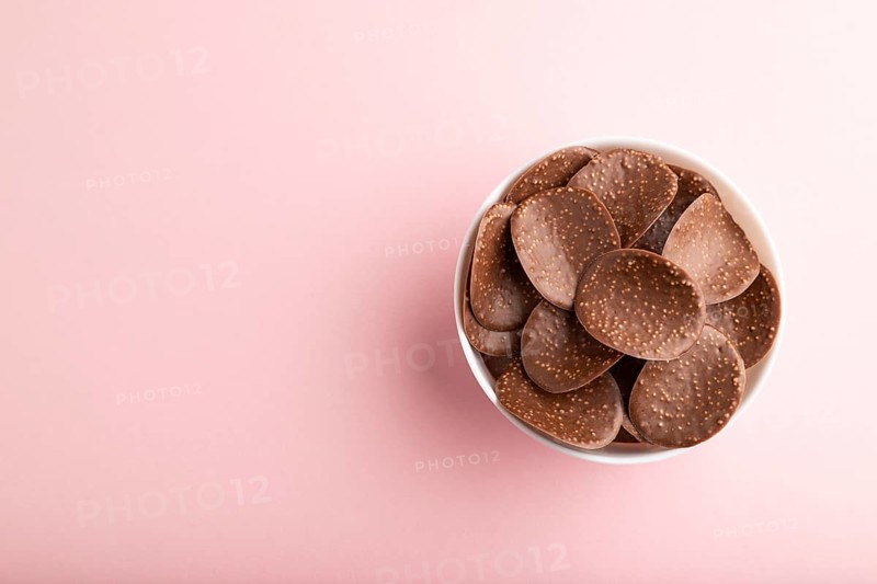 Chocolate chips with caramel on pink pastel background. top view, flat lay, copy space