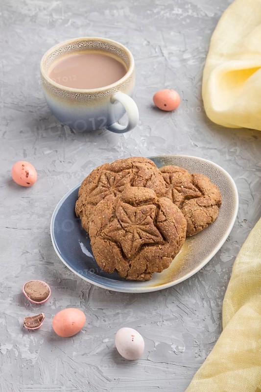 Homemade oatmeal cookies with a cup of cocoa and a yellow textile on a gray concrete background. side view, close up