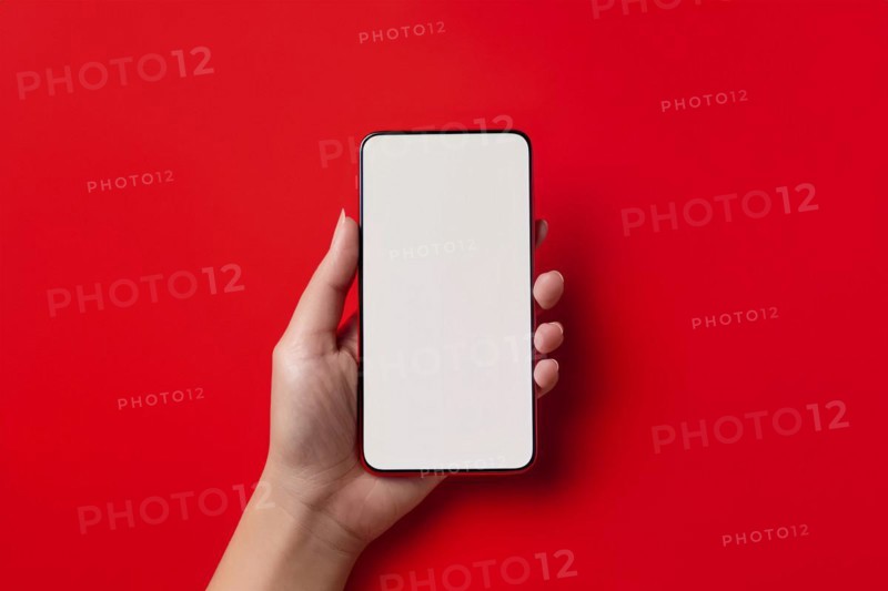 Female hand holding mobile phone with white empty screen in front of red background. KI generiert, generiert, AI generated