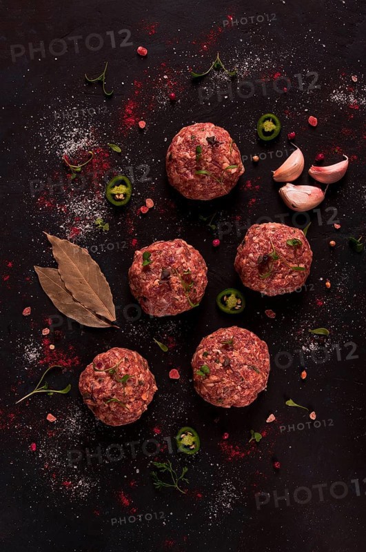 Raw meatballs, with micro greenery, with spices, on a black background, top view, homemade, no people
