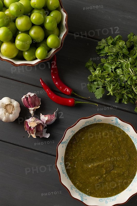 Tkemali sauce, traditional Georgian cuisine, green cherry plum, with ingredients for sauce, cilantro, mint, hot pepper, garlic, on a wooden table, close-up, rustic, food background, no people, selective focus, sauce, green sauce, tkemali, georgian cuisine, homemade