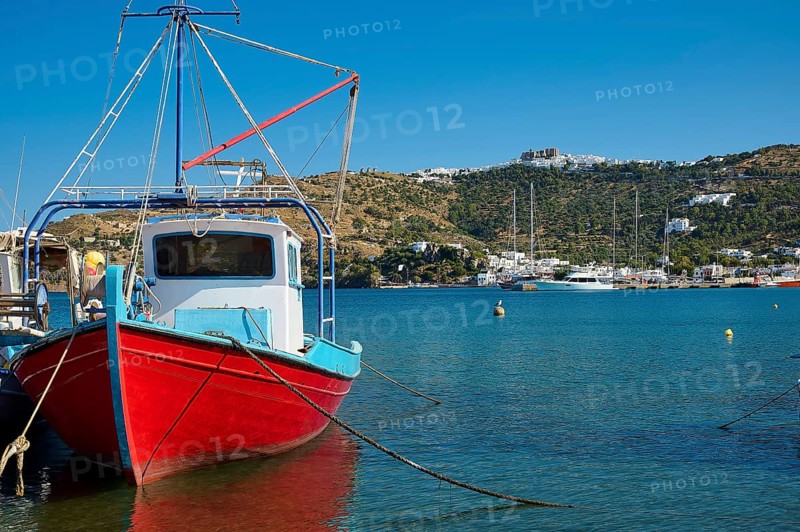 Fishing boat in a quiet harbour, surrounded by blue sea, coast and a clear sky, Skala, Patmos, Dodecanese, Greek Islands, Greece, Europe