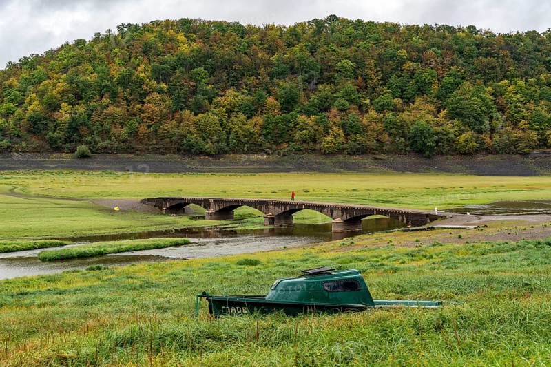 The Edersee, near Waldeck, the third largest reservoir in Germany, currently has only just under 13% of its normal level, the lake was last full in May 2022, dried out due to lack of rain, Asel bridge, exposed by the low water, stranded fishing boat, otherwise flooded, the lake shore and the lake bottom is overgrown with fresh grass, Hesse, Germany, Europe