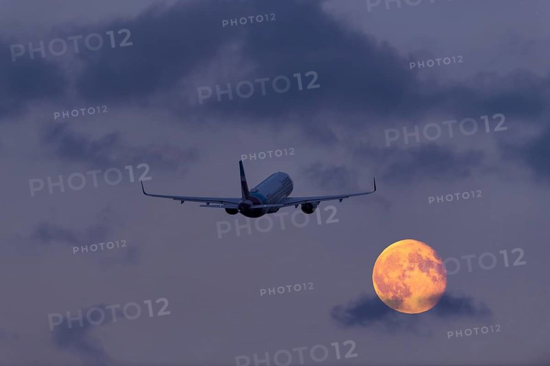 An aeroplane flies through the cloudy sky at night in front of a large, shining full moon, super moon, Stuttgart, Baden-Württemberg, Germany, Europe