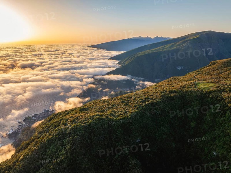 Aerial view of sunrise above clouds and green hills at Fanal mountain, Madeira island, Portugal, Europe