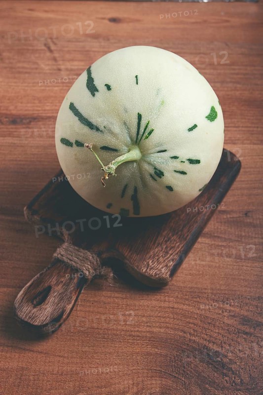 Dino melon, white with green stripes, small size, on the table, close-up, no people