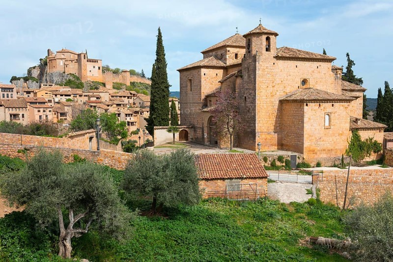 A historic town with medieval buildings and a stone church surrounded by cypresses and trees under a blue sky, collegiate church on the hill, Colegiata de Santa María la Mayor, parish church of San Miguel, Alquézar, Alquezar, Huesca, Aragón, Aragon, Pyrenees, Spain, Europe