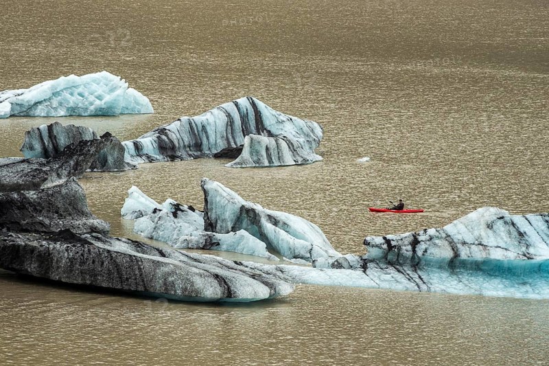 Single kayaker in red kayak, glacial lake at the glacier solheimajökull, icebergs on the lake, Iceland, Europe