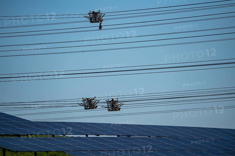 Construction of a new line route, 380 KV extra-high voltage line between Osterath and Gohr, near Neuss, fitters in line trolleys, on the conductor ropes, installing field spacers at great heights, solar park on a disused landfill site, North Rhine-Westphalia, Germany, Europe