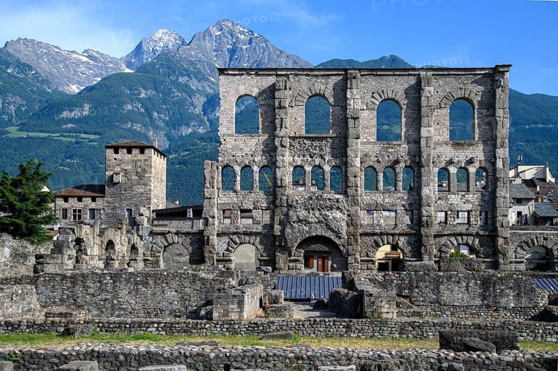 View of facade remains of wall ruins of ancient Roman theatre with window arches in open-air museum Aosta in Aosta Valley, in the background mountain range of high Alps, Aosta, Aosta Valley, Valle d'Aosta, Vallee d'Aoste, Italy, Europe