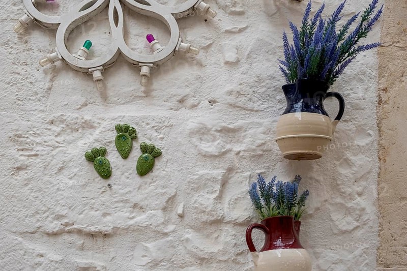 Jugs with artificial flowers hanging as decoration on a white house wall, Cisternino, Valle d'Itria, Itria Valley, Apulia, Italy, Europe