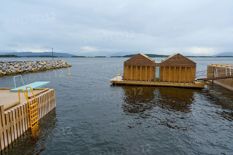 Outdoor sea pool by the fjord with small wooden sauna huts, overcast sky and calm water, Molde, Romsdal, Norway, Europe