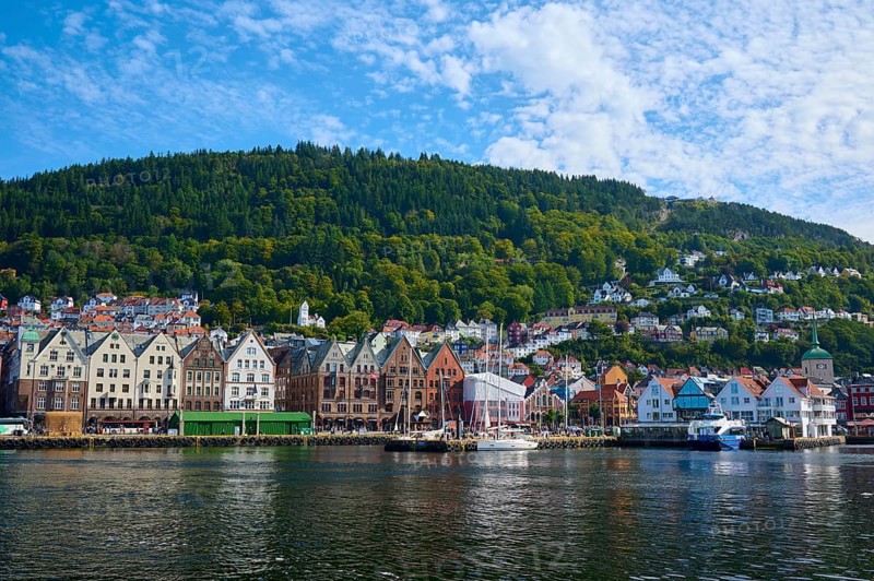 Picturesque coastal town with colourful houses and densely wooded hills in the background, boats on the shore, Bryggen, Bergen, Vestland, Norway, Europe