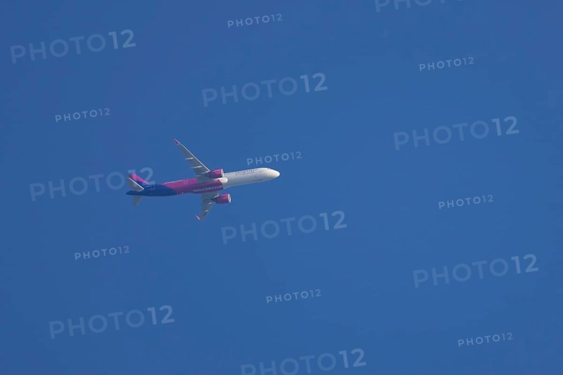 Airbus aircraft of Wizz air airlines flying across a blue sky, England, United Kingdom, Europe