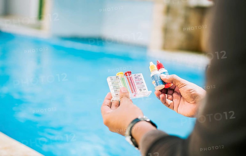 Person testing the PH of the swimming pool. Hand holding tester kit to measure chlorine and ph in swimming pools