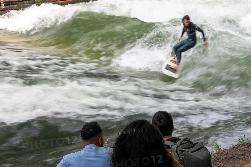 Surfer riding Eisbach wave, onlookers on the shore, Eisbach and wave in the English Garden are known worldwide, Munich, Bavaria, Germany, Europe