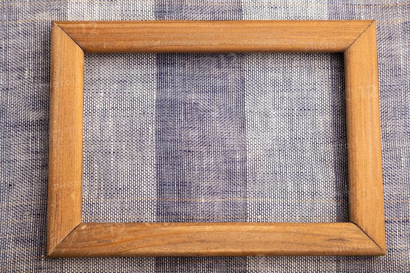 Wooden frame on smooth brown and violet linen tissue. Top view, flat lay, natural textile background and texture