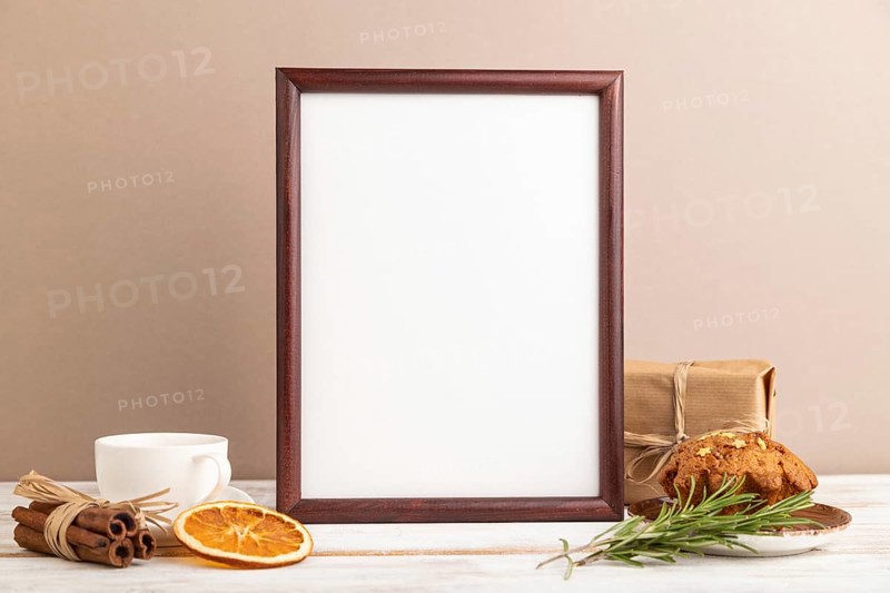 Brown wooden frame mockup with cup of coffee and cake on brown background. Blank, side view, still life