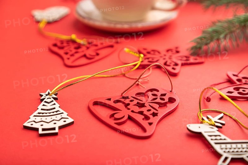 Christmas or New Year composition. Decorations, fir and spruce branches, cup of coffee, on a red paper background. Side view, selective focus, close up