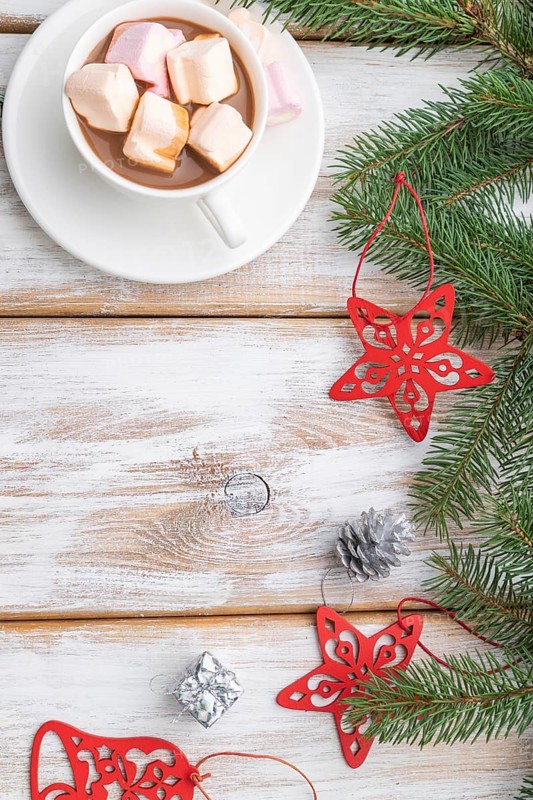 Christmas or New Year frame composition. Decorations, red stars, bells, cones, fir and spruce branches, cup of coffee, on a white wooden background. Top view, copy space, flat lay