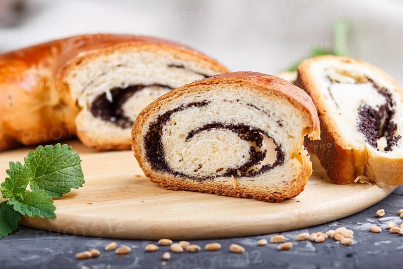 Homemade yeast rolls with poppy seeds and honey on a wooden kitchen board on a black concrete background. side view. close up, selective focus