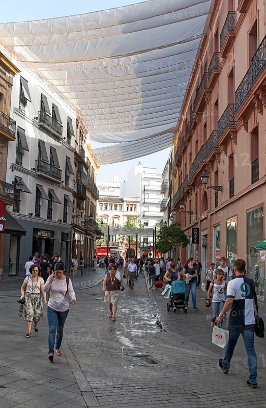 Fabric spread over buildings to provide shade in busy shopping street in central Seville, Spain, Europe