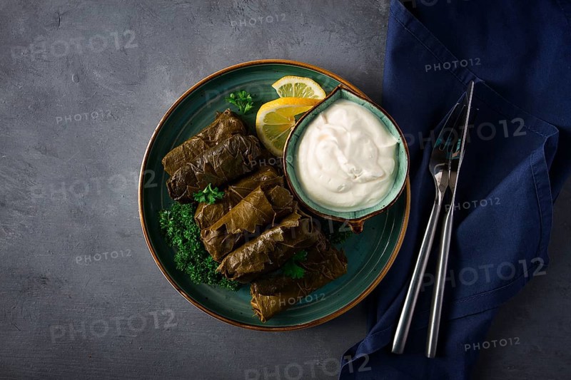 Dolma, cabbage rolls, grape leaves with filling, white sauce, lemon and herbs, rustic, selective focus, no people