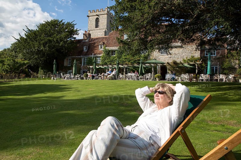 Woman sunbathing in gardens of the Priory Hotel, Wareham, Dorset, England, UK