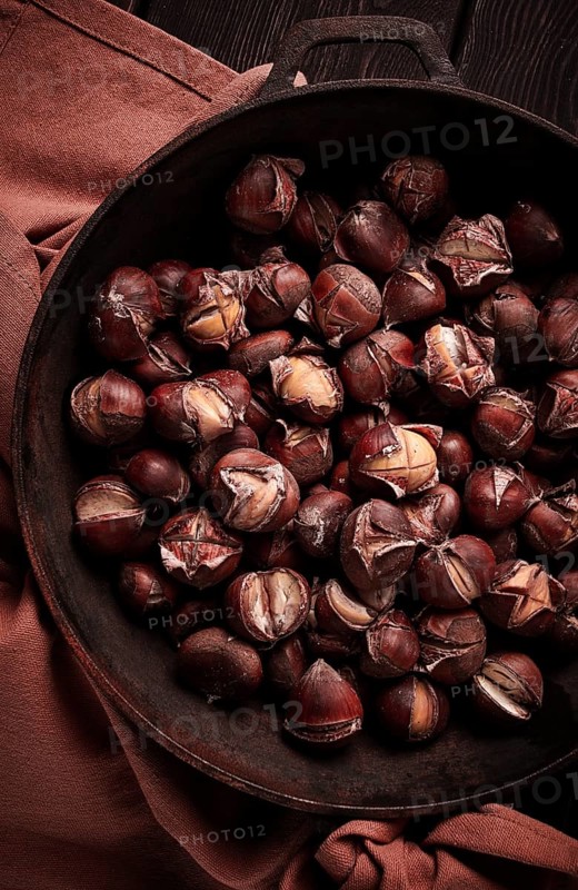 Roasted chestnuts, in an iron pan, wooden table, top view, no people, rustic style