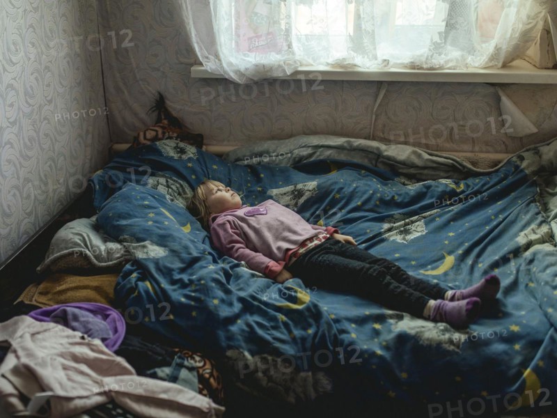 Angelina, 9 years old, on her bed. The village of Borshchivka was under Russian occupation. She has anxiety disorders. Angelina and her grandmother Larisa hid in their house for almost six months in Borshchivka, Raion Isyum, Kharkiv Oblast, Ukraine, Europe