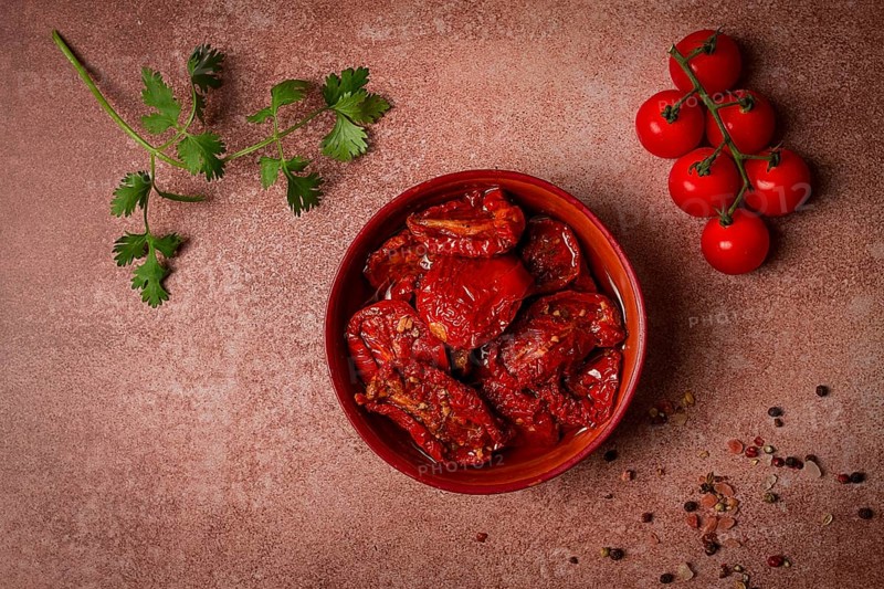 Dried tomatoes, in a bowl, top view, on a brown background