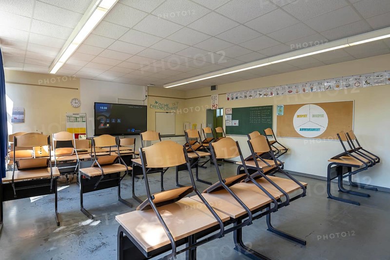 Classroom of a fourth grade, after school, the building is older but in good condition, modern teaching materials, interactive, digital whiteboard