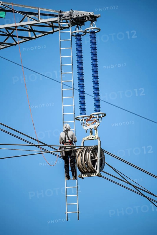 Construction of a new line route, 380 KV extra-high voltage line between Osterath and Gohr, near Neuss, fitter on ladder at great height, tensioning the lines, North Rhine-Westphalia, Germany, Europe