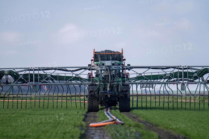Tractor with boom for spreading liquid manure, on a field, fertilisation