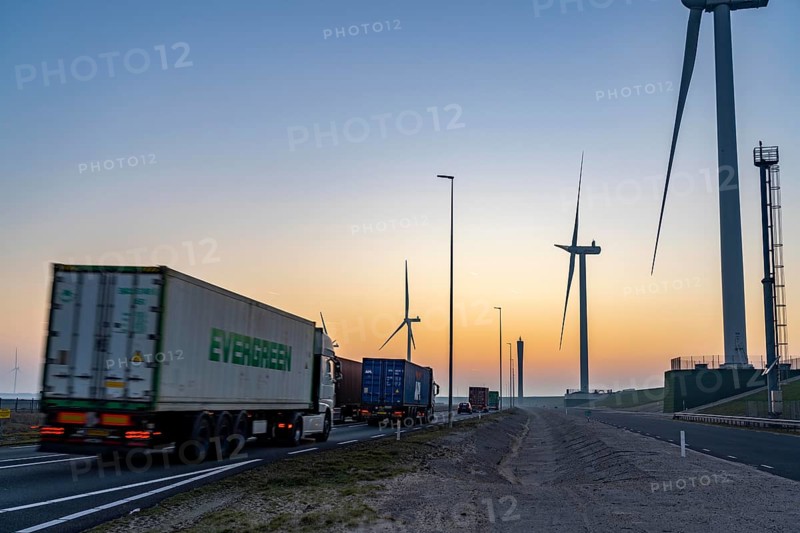 Lorry on the road from Euromax Terminal Rotterdam, ENECO wind farm on the dike around the port of Maasvlakte 2, 22 wind turbines with a capacity of 116 megawatts, sunset, Rotterdam, NetherlandsEvergreen Container