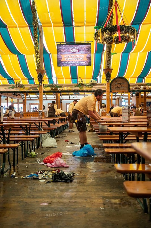 Employees cleaning the marquee after an event, rubbish scattered on the floor, Canstatter Wasen, Stuttgart, Germany, Europe