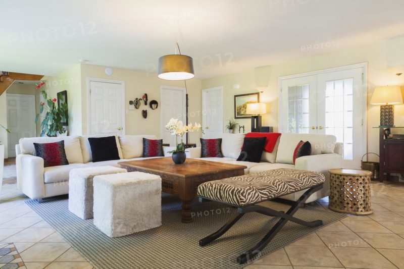 Beige upholstered sofas with colourful cushions, wooden coffee table and zebra motif ottoman in living room inside a luxurious residential home, Quebec, Canada, North America