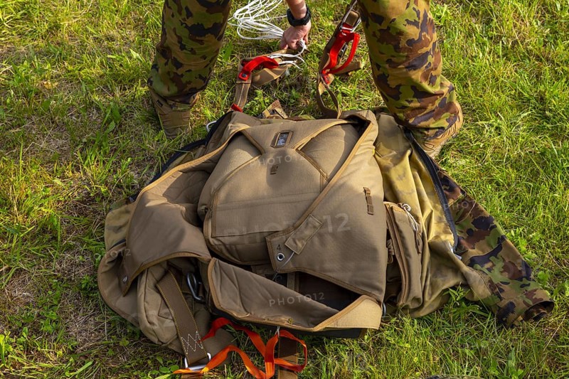 Military Parachuter Standing on the Grass with His Parachute in Switzerland
