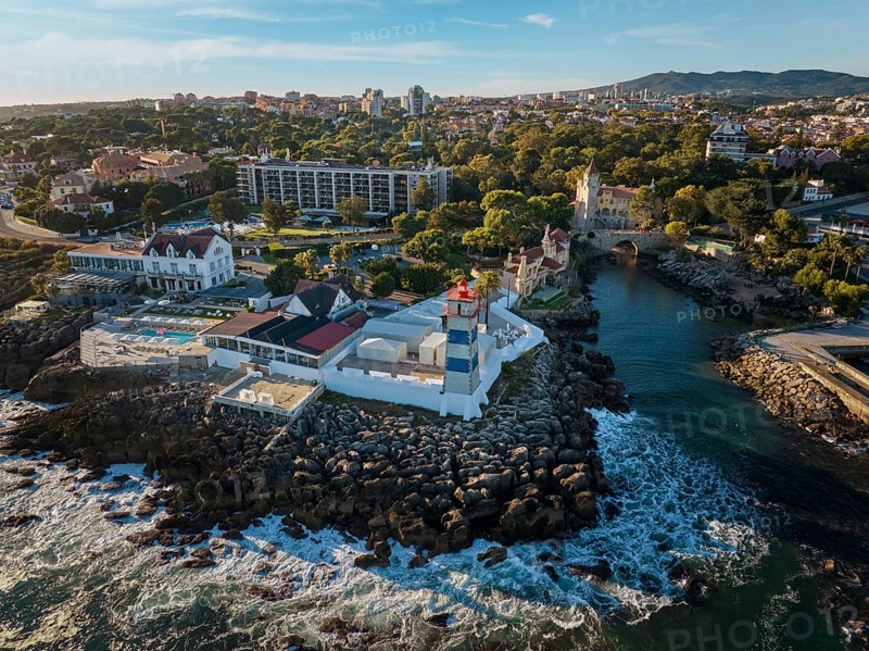 Aerial view of Santa Marta lighthouse and Cascais marina with moored yacht boats with Cascais cityscape, Portugal on sunset