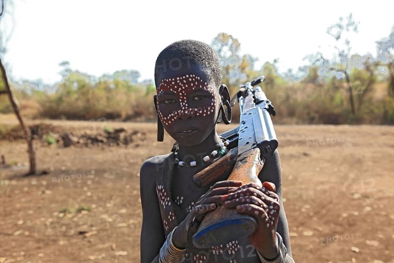 South Ethiopia, in Maco National Park, Mursi tribe, Mursi boy with painted face and rifle, Ethiopia, Africa