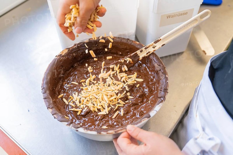 Almonds are added to a dark chocolate mixture in a bowl, Production Burch Schokolade, Haselstaller Hof, Gechingen, Germany, Europe