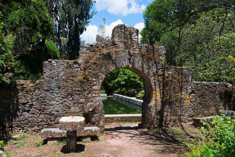 Ein alter Steinbogen führt in einen grünen Garten an einem sonnigen Tag, Mata Nacional do Buçaco, National-Wald von Bussaco, Bucaco, Mealhada, Beira Litoral, Portugal, Europe