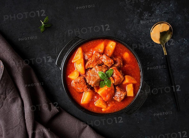 Stew with potatoes, in tomato sauce, with spices and herbs, close-up, no people, on a black background