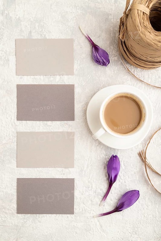 Gray paper business card mockup with spring snowdrop crocus flowers and cup of coffee on gray concrete background. Blank, business card, top view, flat lay, copy space, still life. spring concept