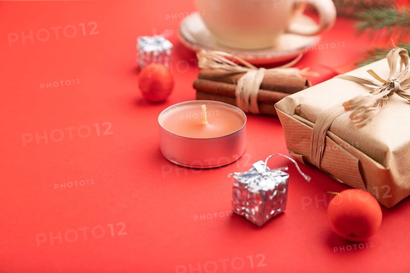 Christmas or New Year composition. Decorations, box, cinnamon, fir and spruce branches, cup of coffee, on a red paper background. Side view, copy space, selective focus