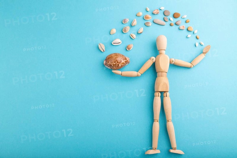 Wooden mannequin juggling sea shells on blue pastel background. copy space, isolated, travel, vacation, summer concept