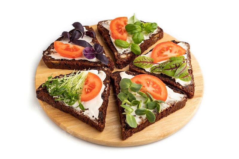 Grain rye bread sandwiches with cream cheese, tomatoes and microgreen isolated on white background. side view, close up